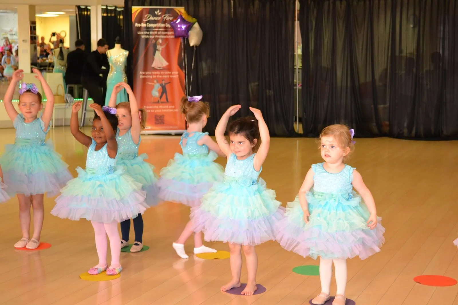 Ballet performers in pastel tutus raise their arms during the recital