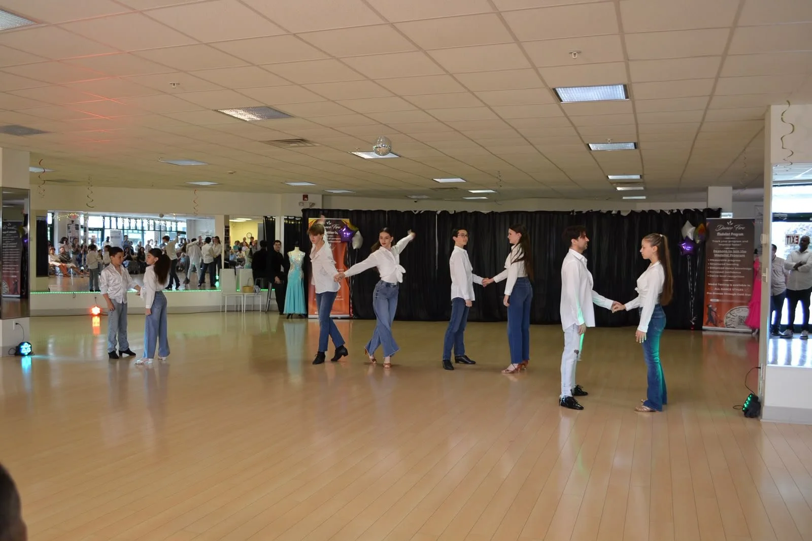 Young performers in white shirts and jeans dance in a line