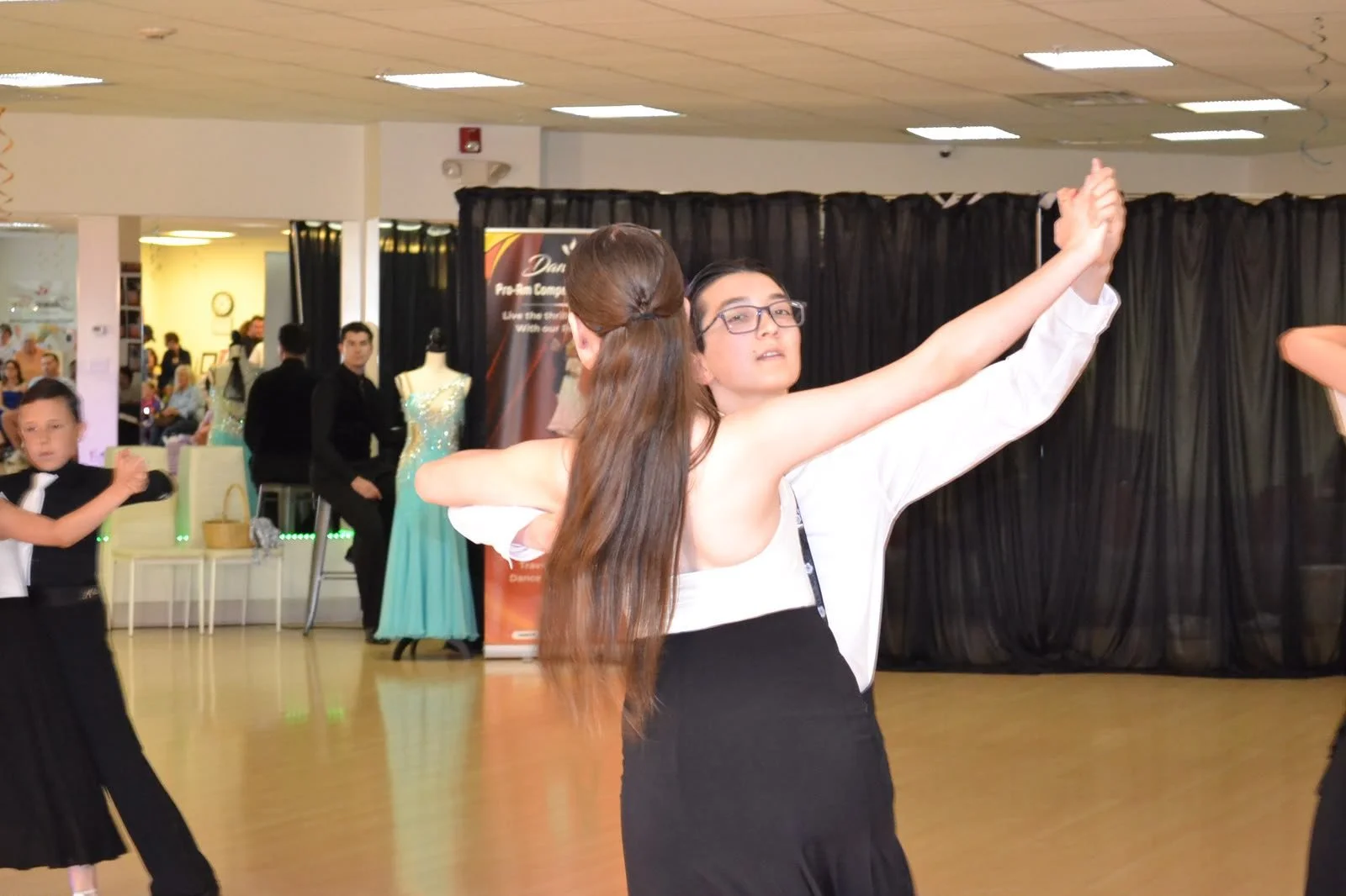 A youth ballroom couple turns together during the recital