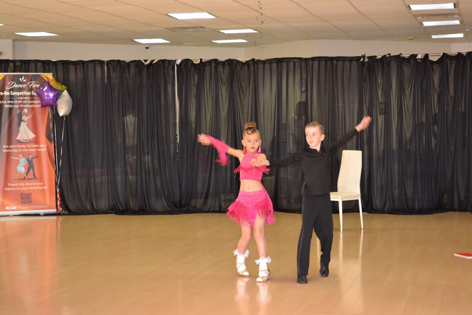 A young couple performs a partnered routine in pink and black costumes