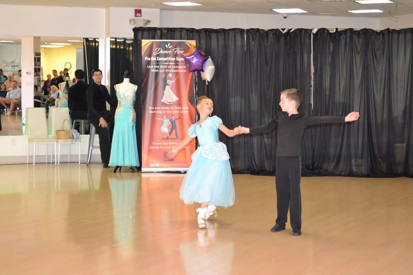 A young ballroom couple performs with a flowing pale blue dress