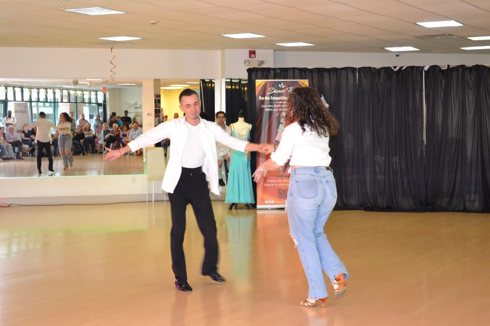 Two young performers dance together in white shirts and jeans
