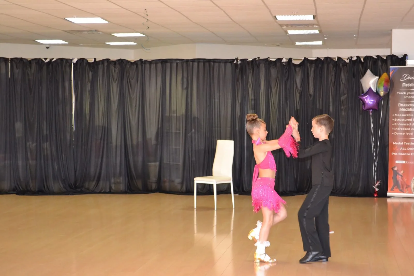 A young couple dances beside a chair used in their recital routine
