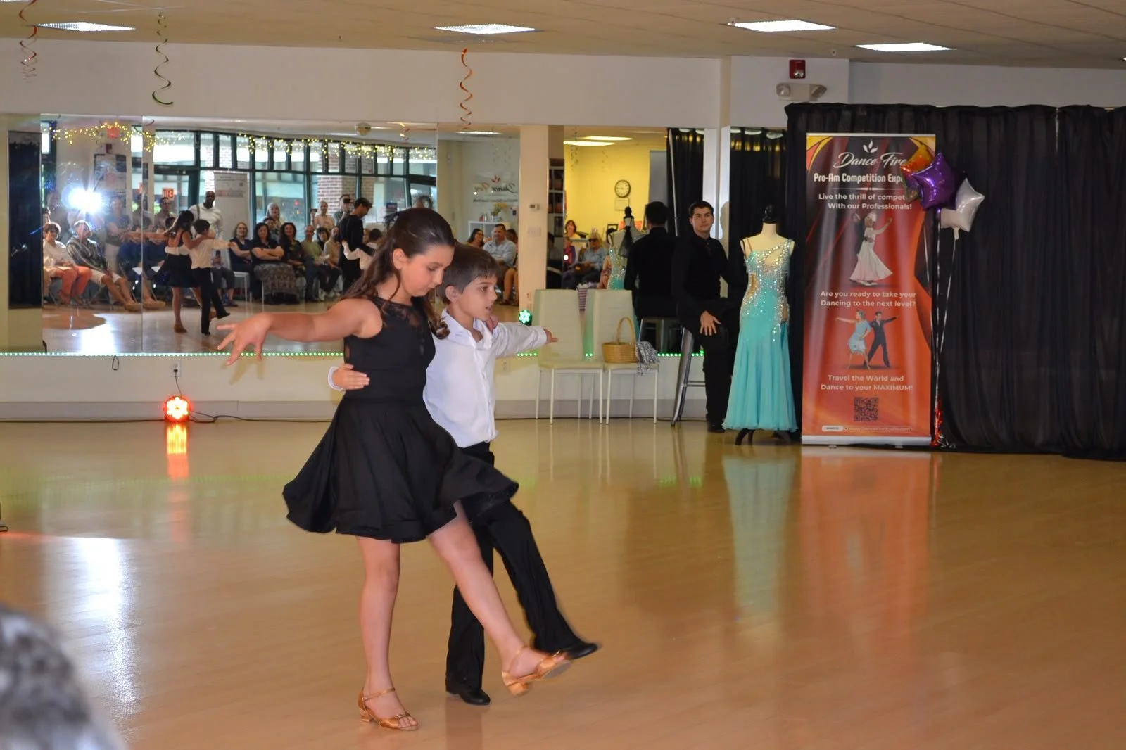 A young dance couple turns together in black recital attire