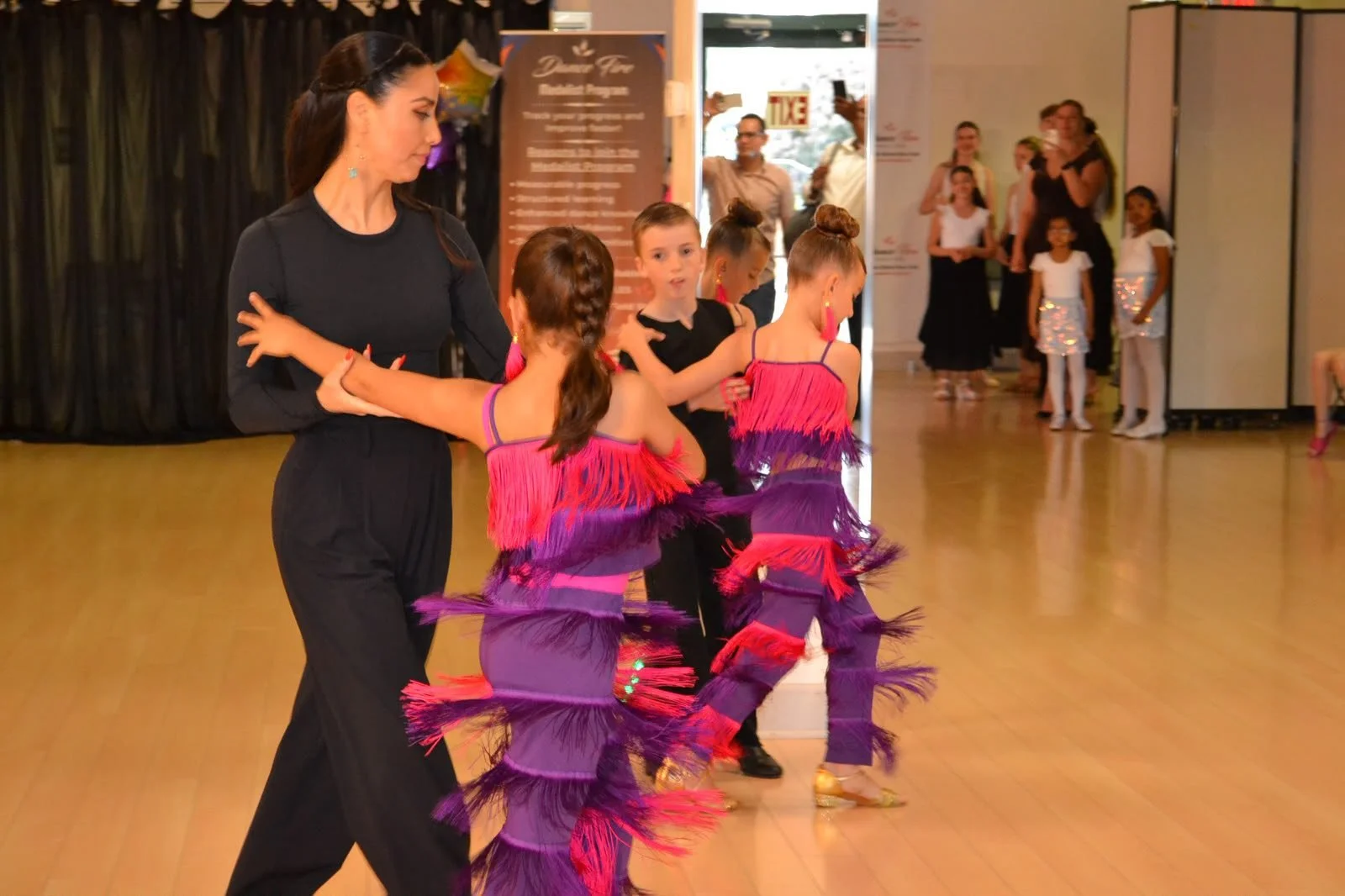 An instructor supports young performers in purple recital costumes