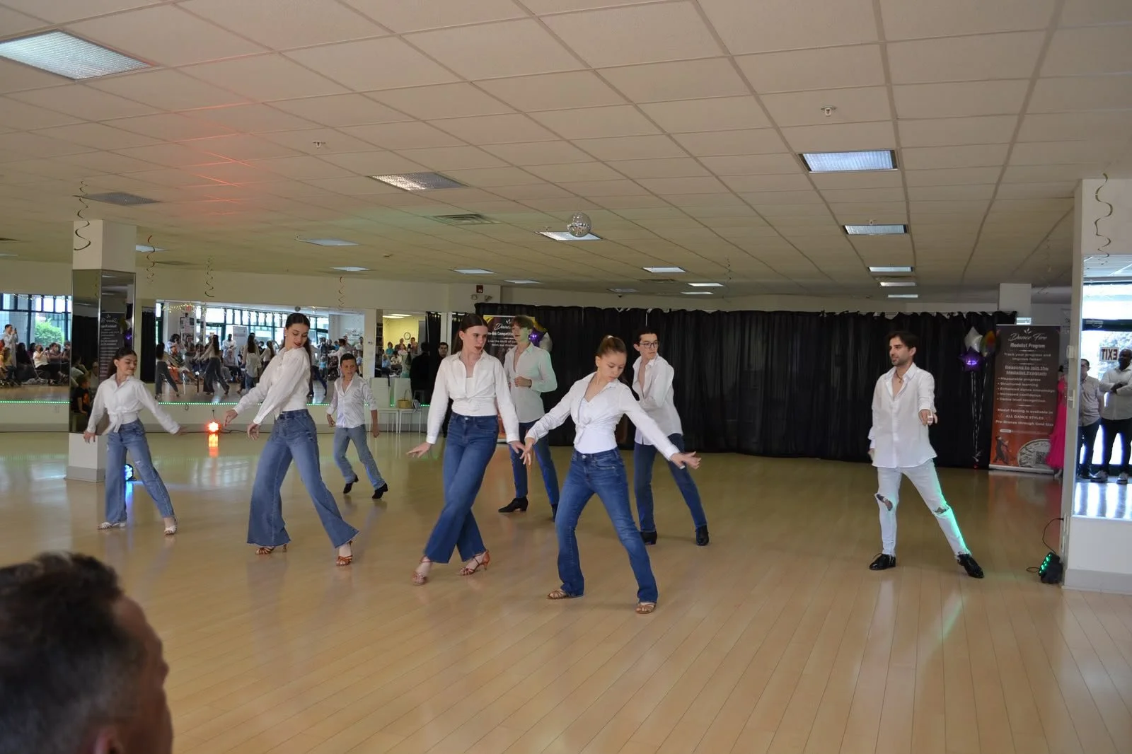 Youth dancers in white shirts and jeans perform a coordinated group routine