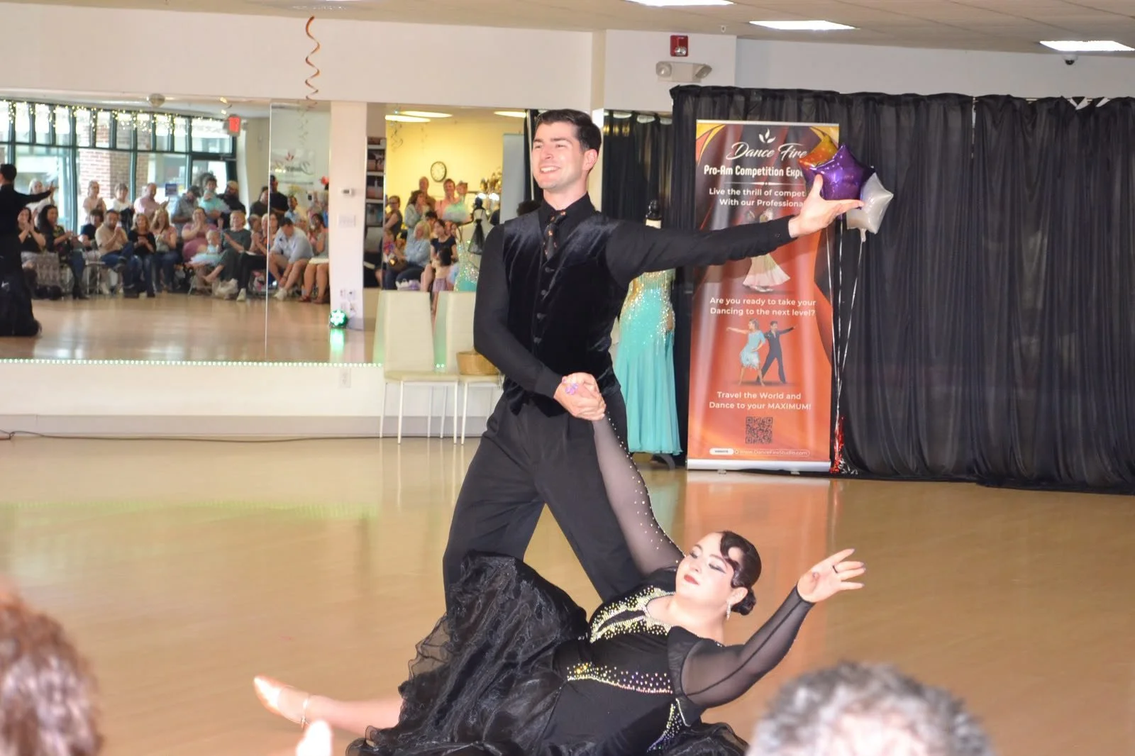 A dance couple performs a dramatic floor-level dip during the recital