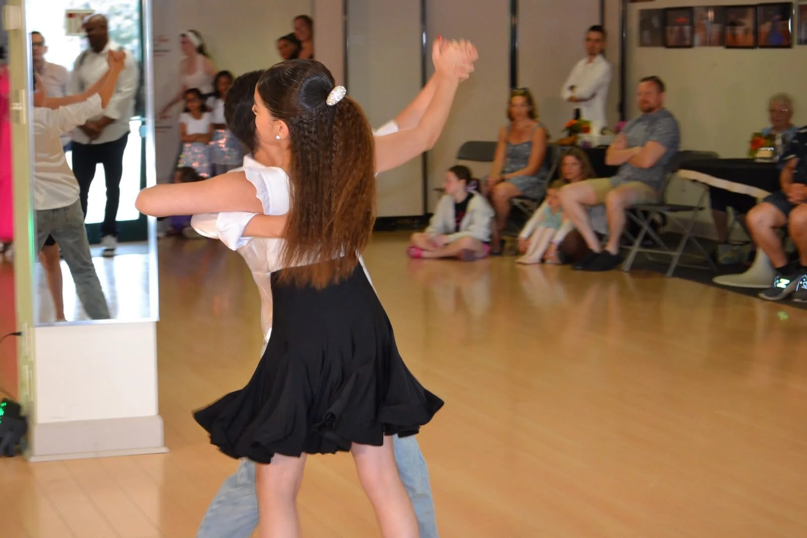 A youth ballroom pair dances before the seated recital audience