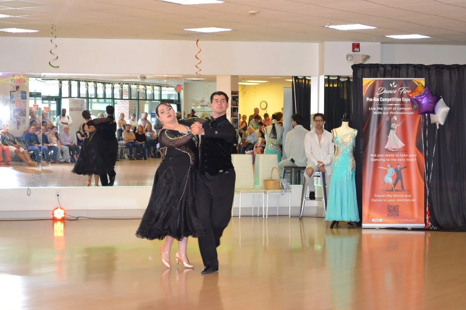 A young dancer in a black skirt turns toward the recital audience
