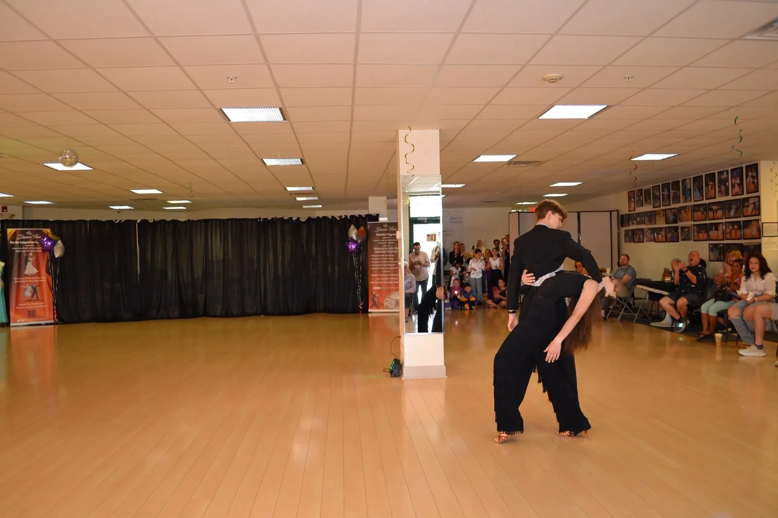 A dance couple performs a low partnered pose during the recital demonstration