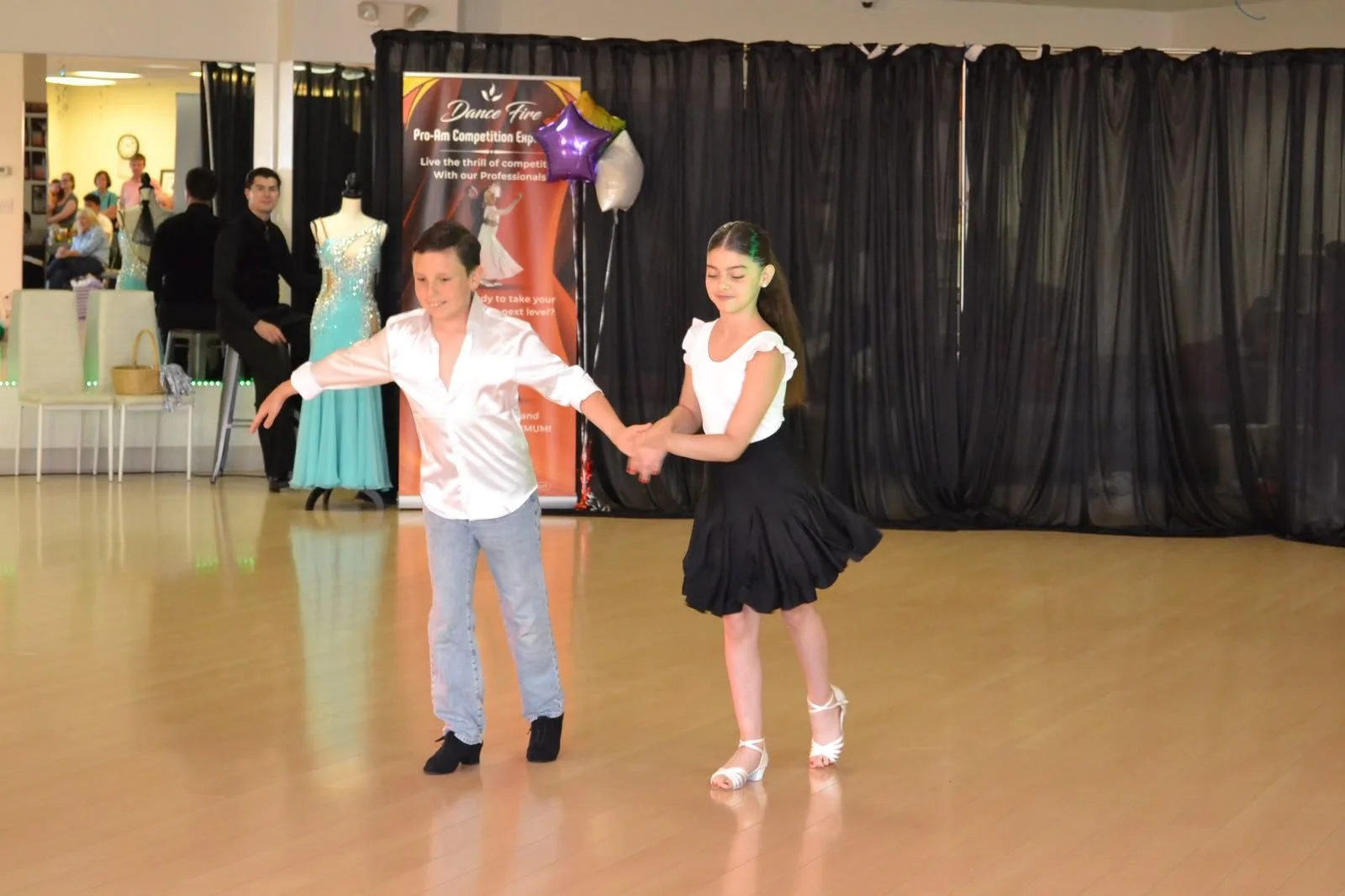A young dance pair performs an extended-arm movement together
