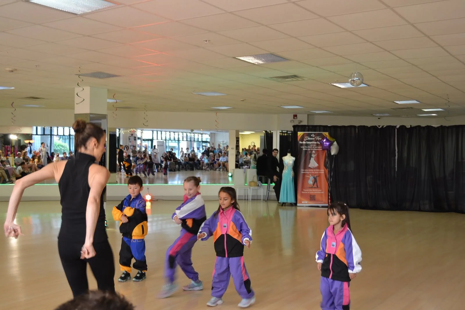 An instructor guides children in purple costumes through their group routine