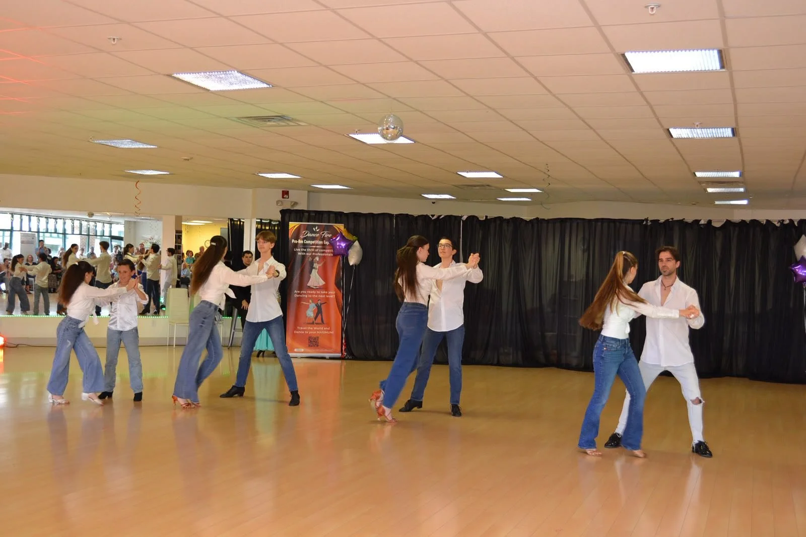 Youth dancers in white shirts and jeans perform a synchronized group routine