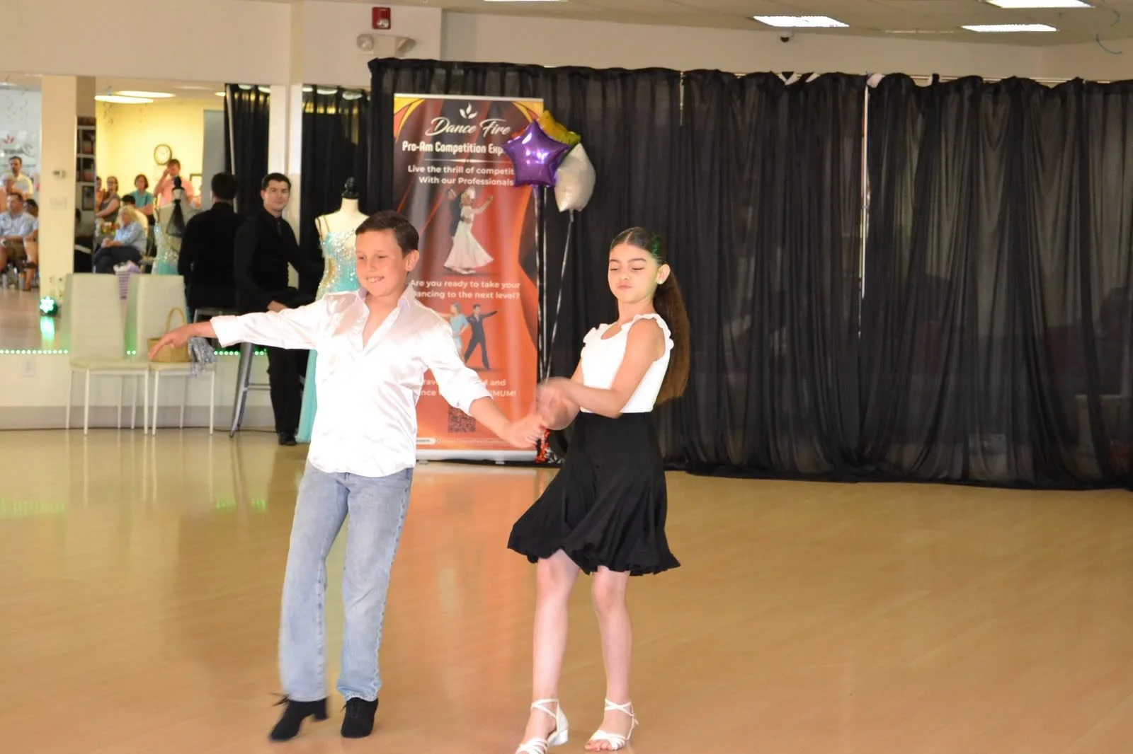 A young couple performs a partnered movement in white and black recital attire