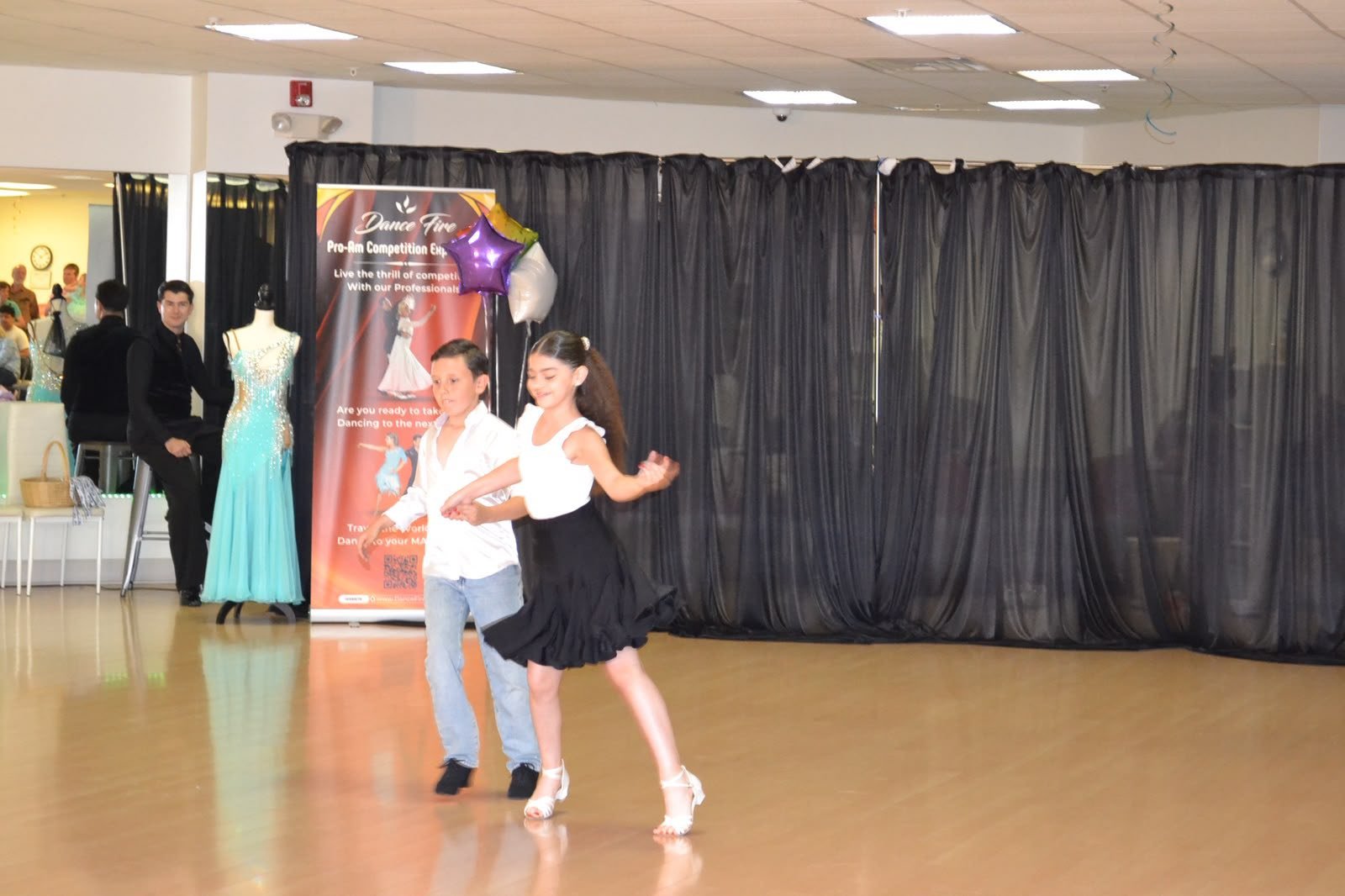 A youth dance pair performs together on the studio floor