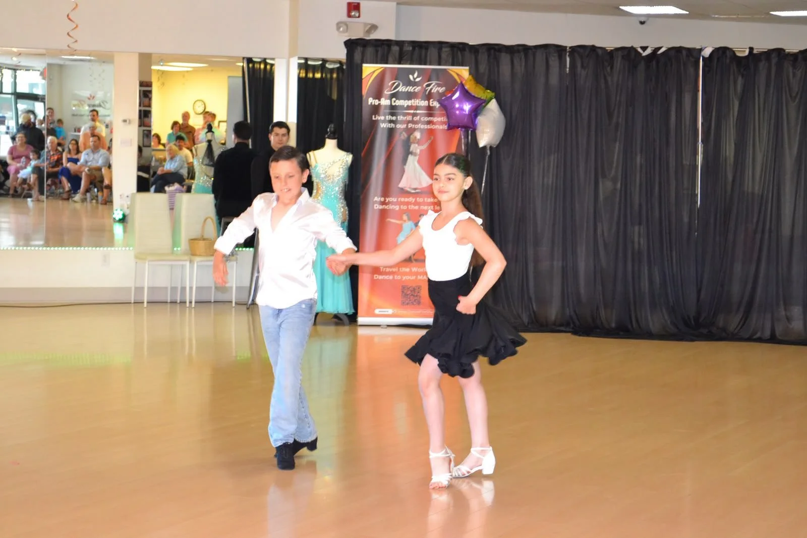 A young pair performs a recital routine in white and black dance attire