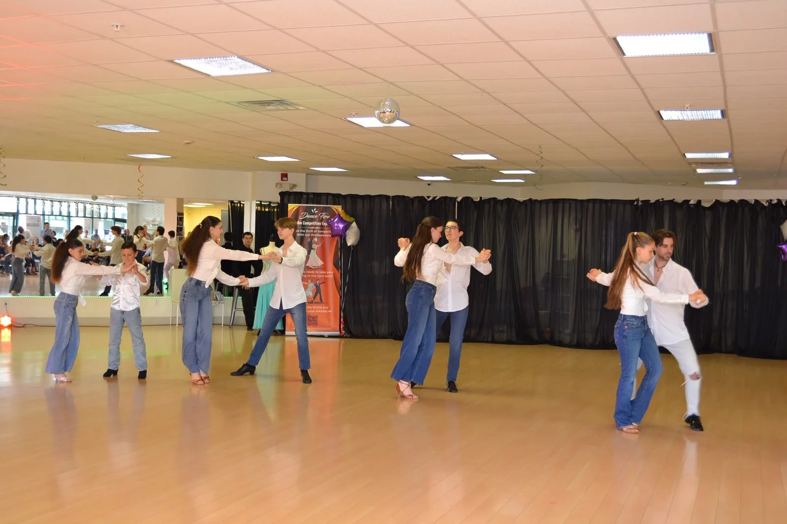 Young dancers in white shirts and jeans perform together in formation