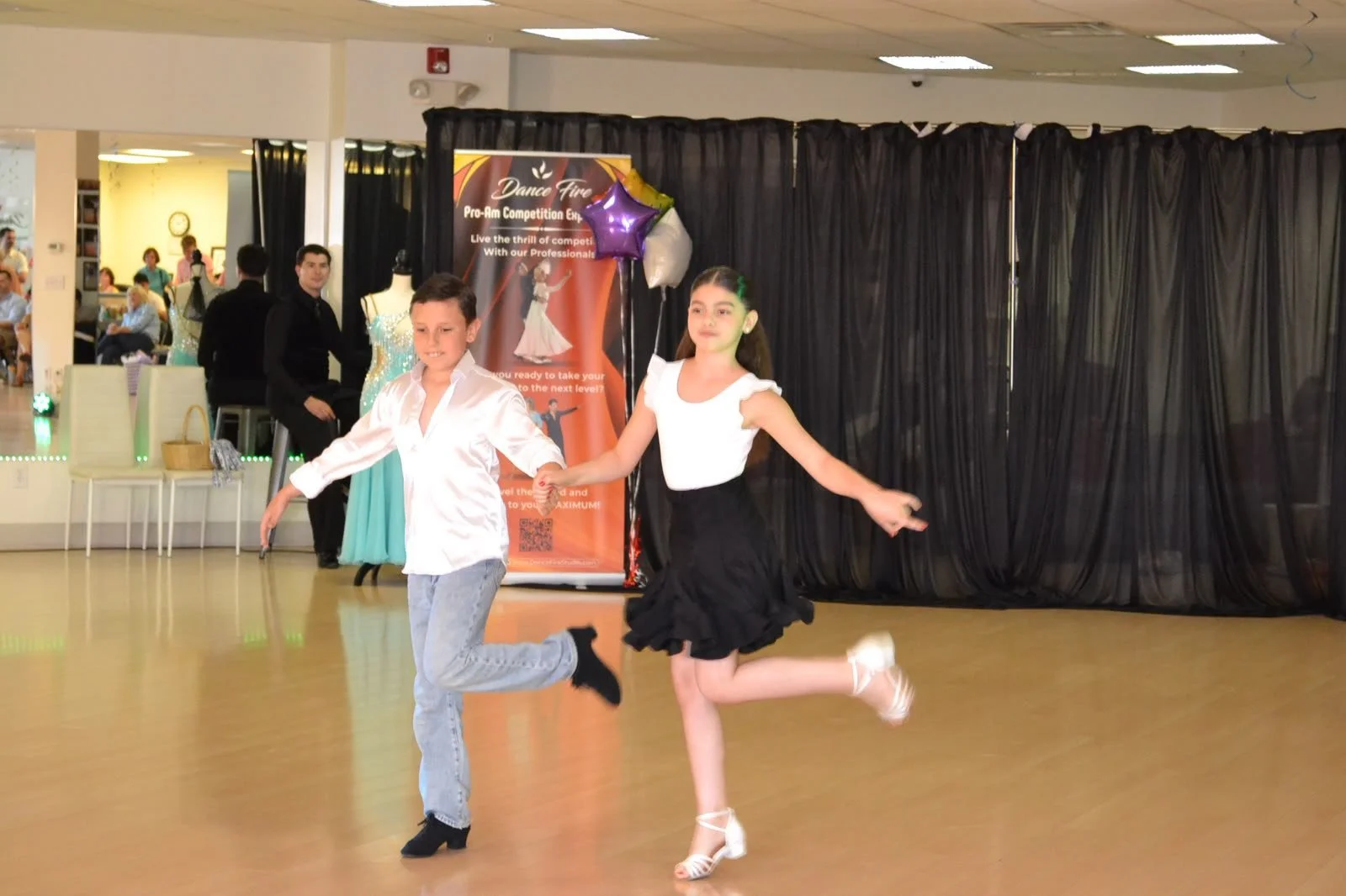 A youth dance couple extends their arms during a partnered routine