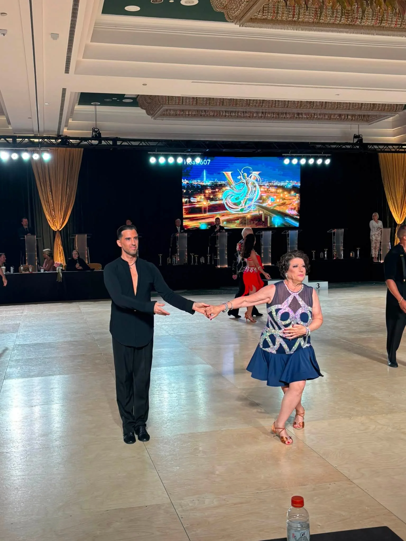 A competition pair walks together across the Virginia ballroom floor