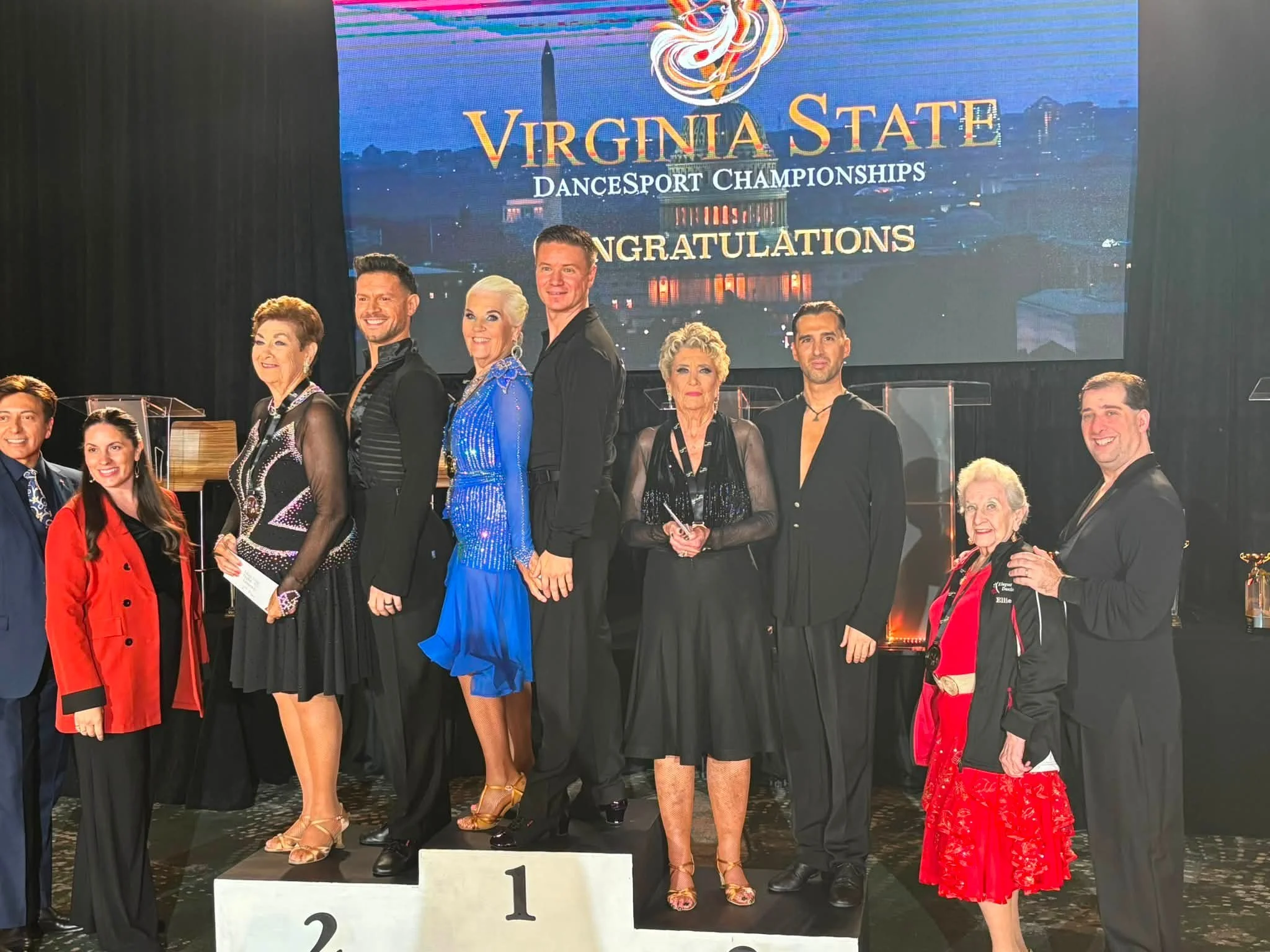Dancers stand together beneath the Virginia State championship display