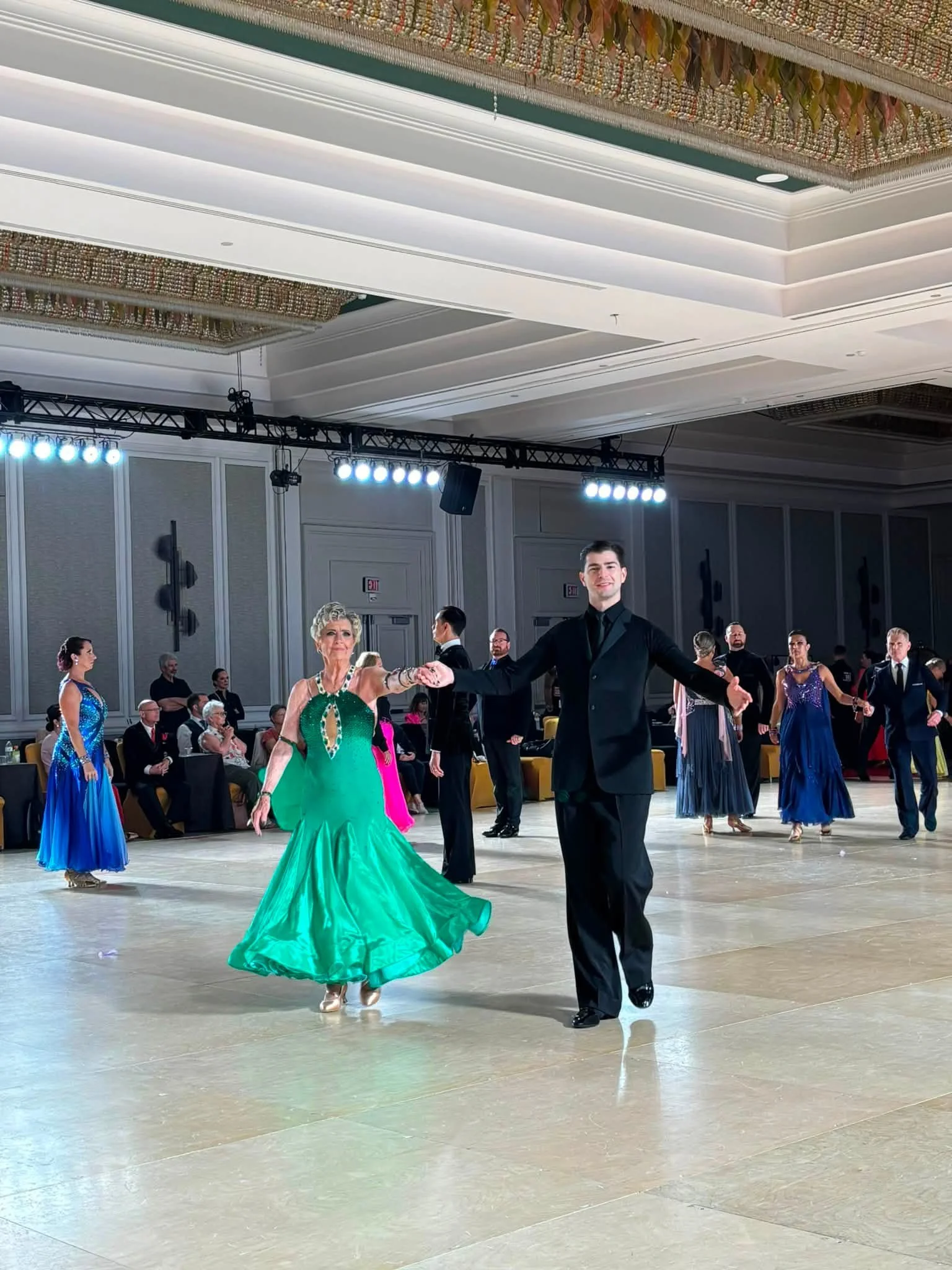 A ballroom couple in green and black dances at Virginia DanceSport