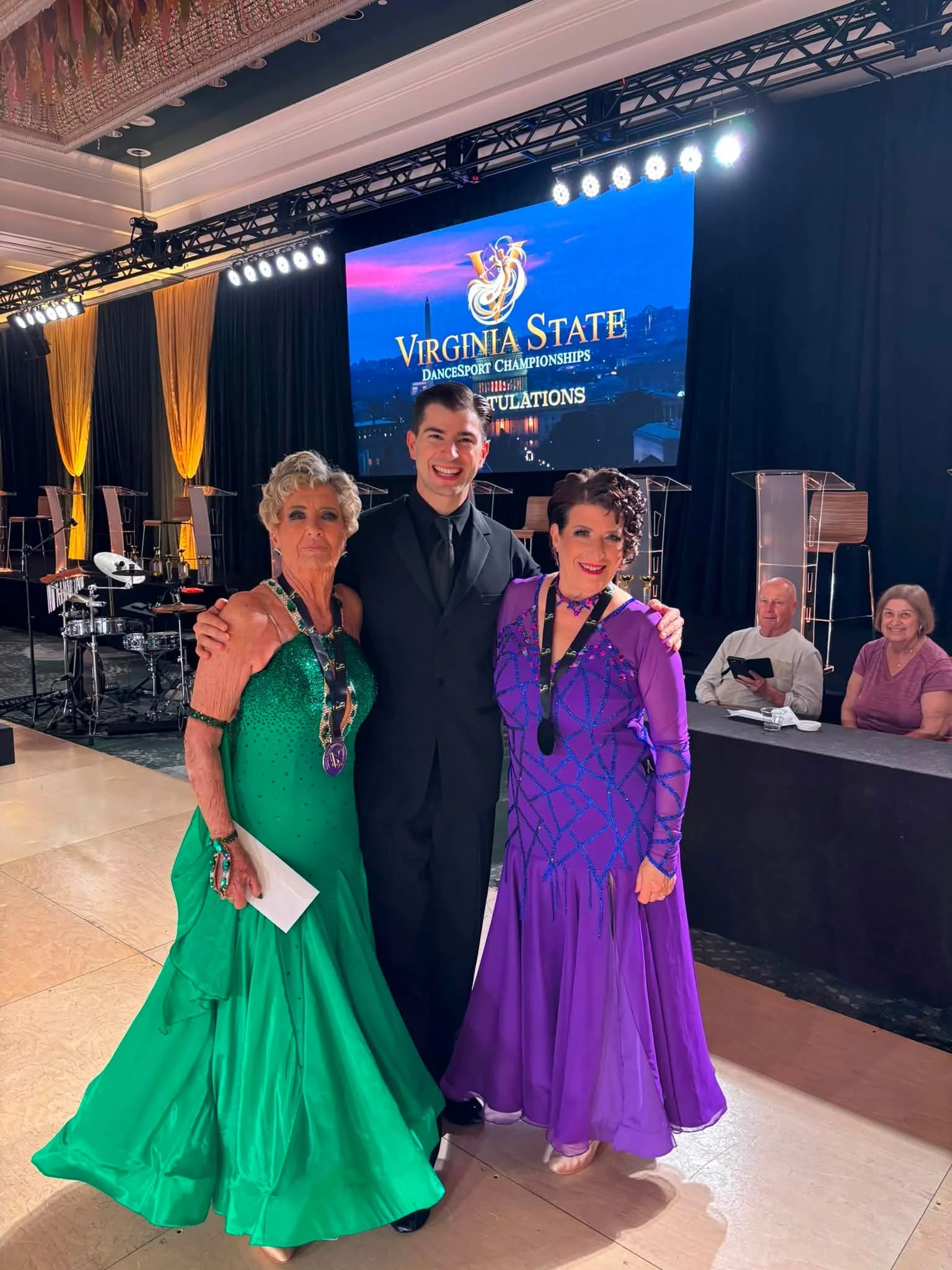 Three Dance Fire competitors pose in green, purple, and black ballroom attire