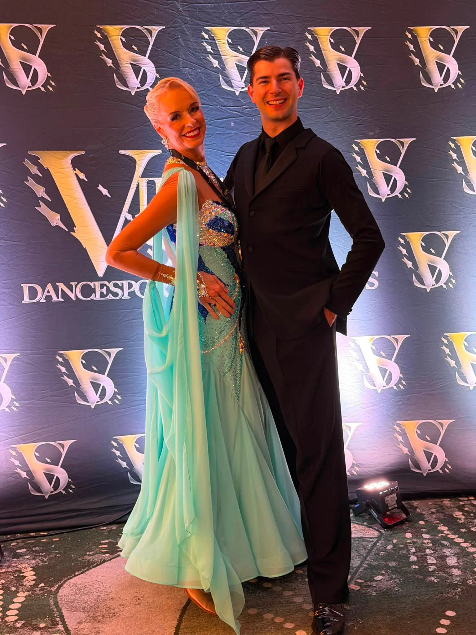 A competition pair poses at the Virginia DanceSport photo backdrop