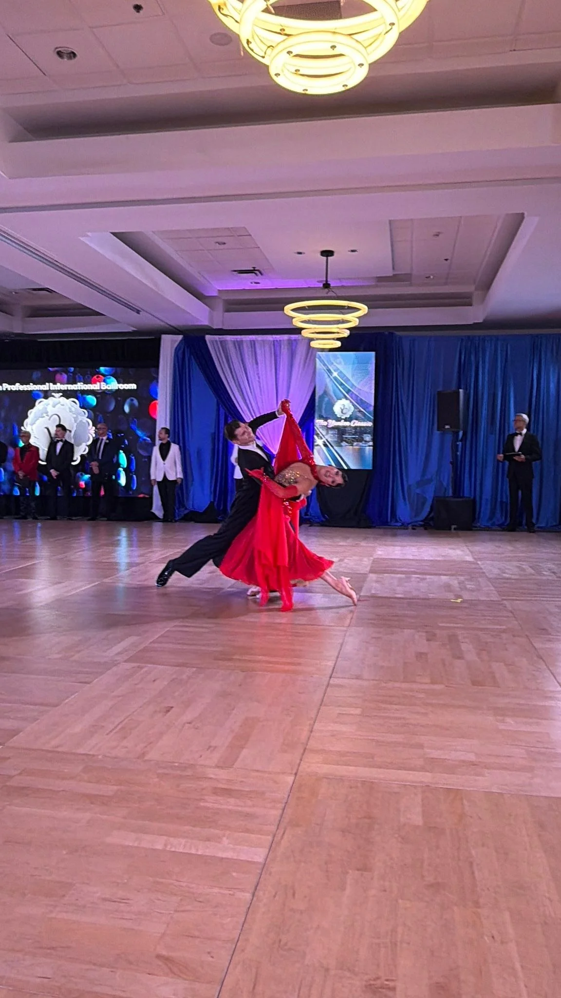 A couple dances across the Yankee Classic ballroom floor in red competition attire