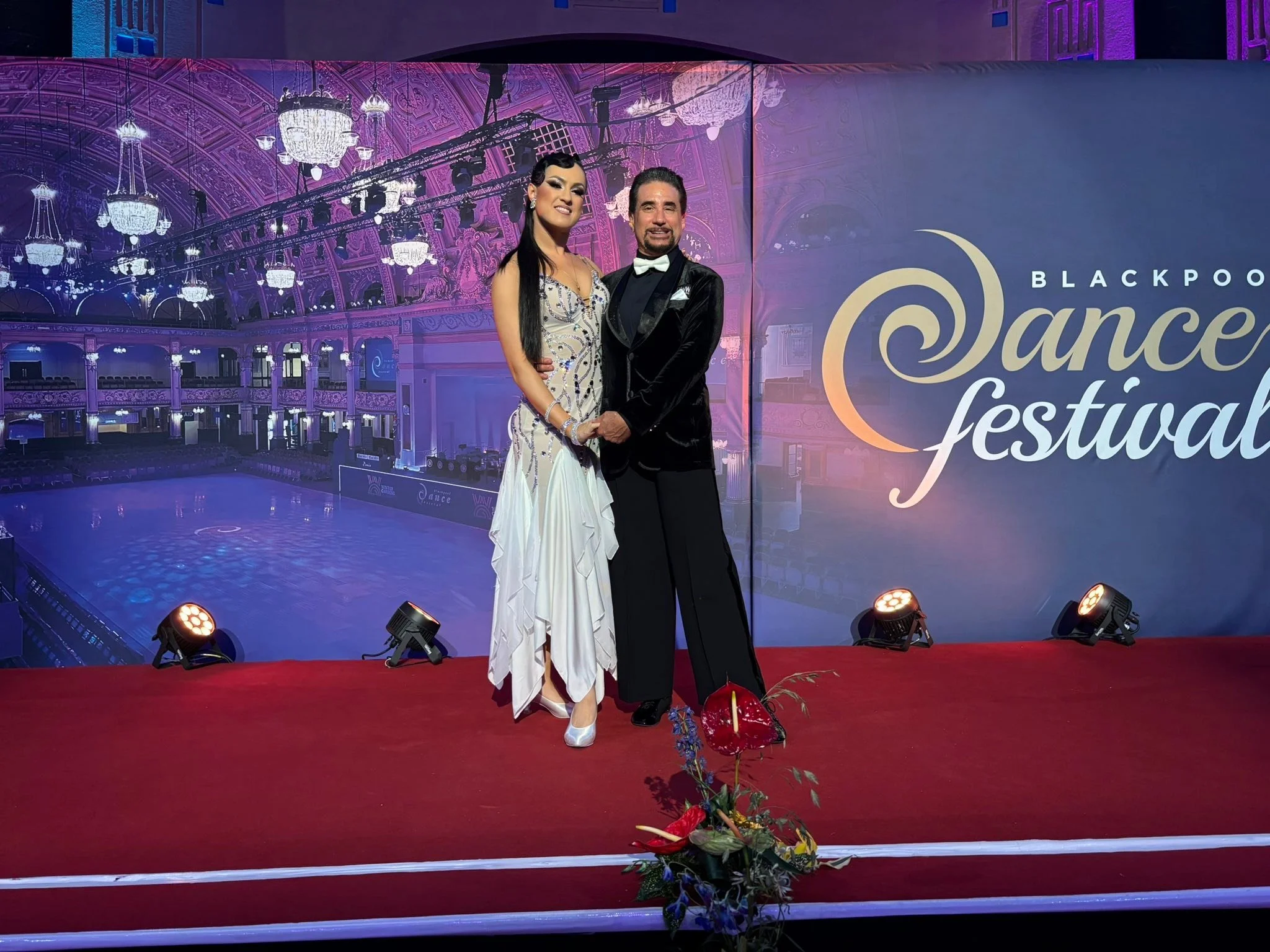 A Dance Fire competition pair poses at the Blackpool Dance Festival backdrop