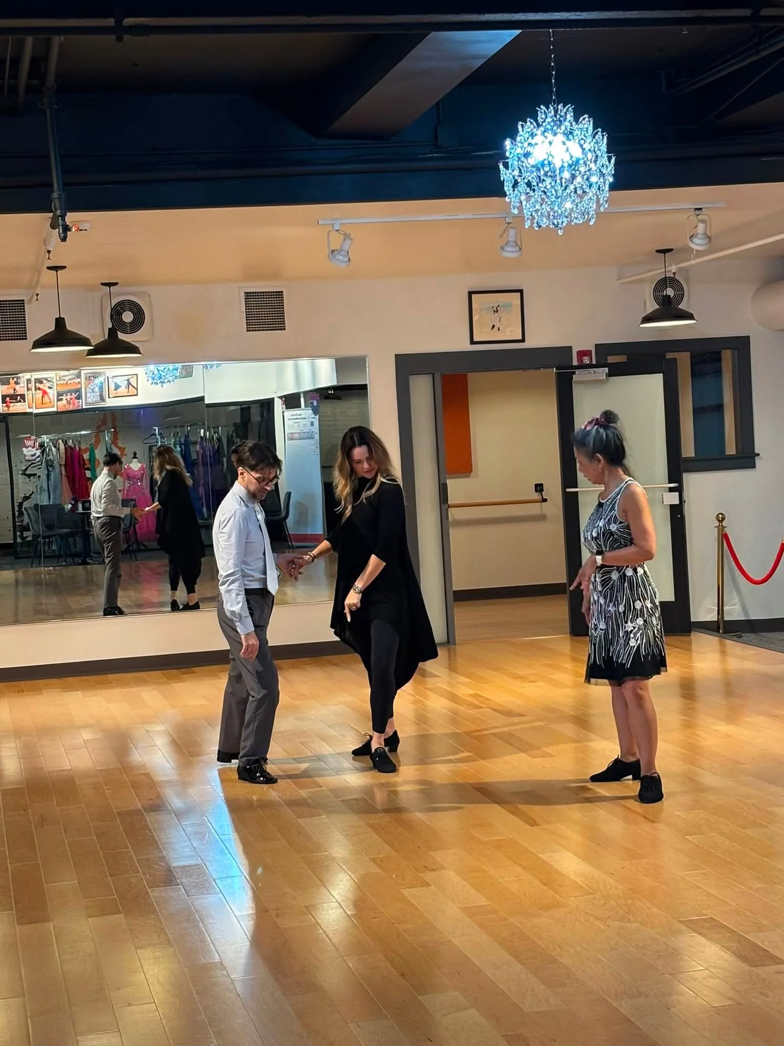 A coach observes two dancers practicing partnered movement