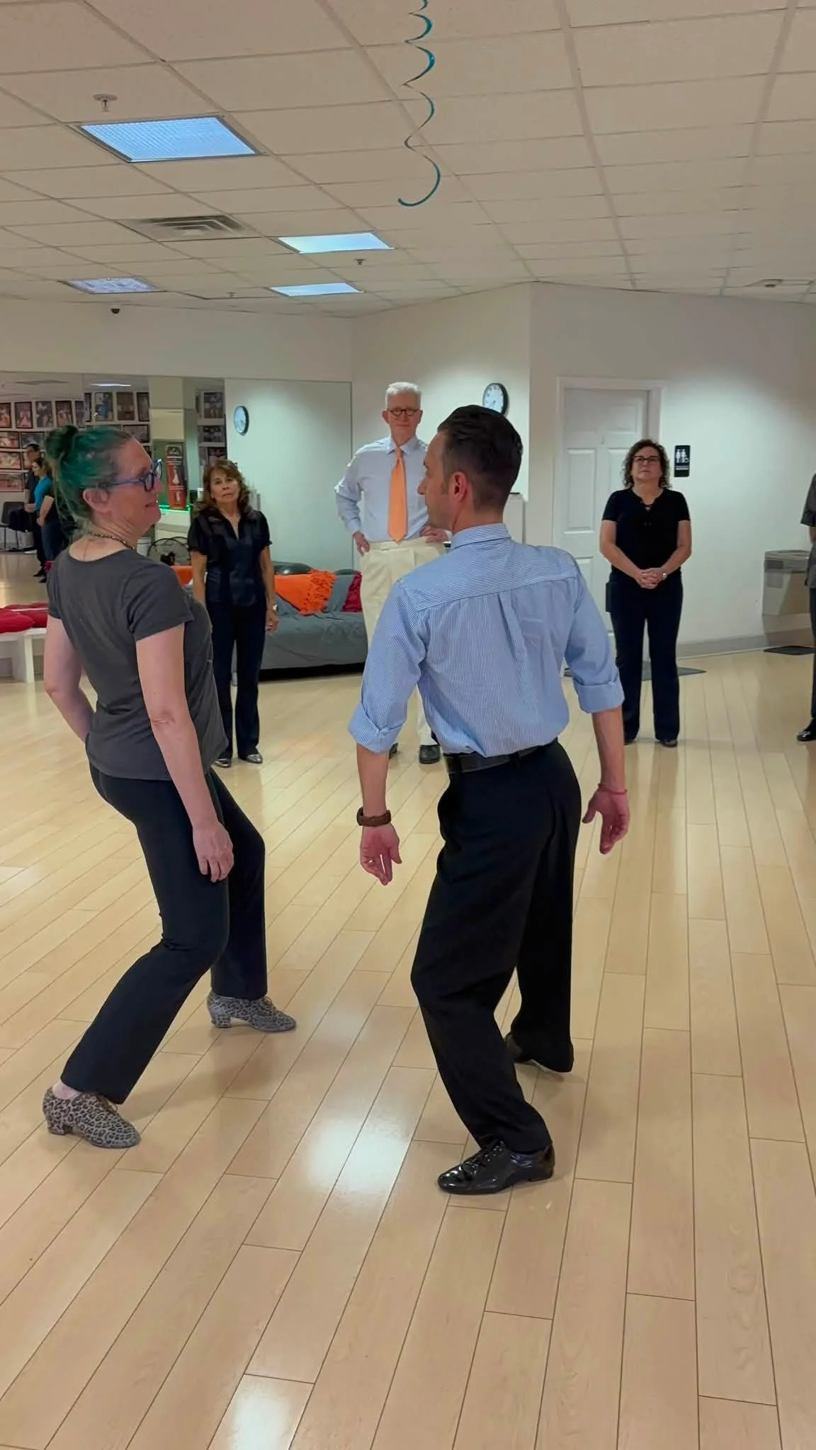 Two coaching participants practice together beside the studio mirrors