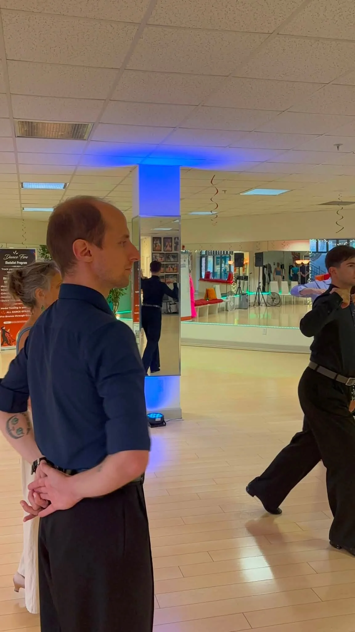 A coaching participant watches a movement demonstration near the studio mirrors