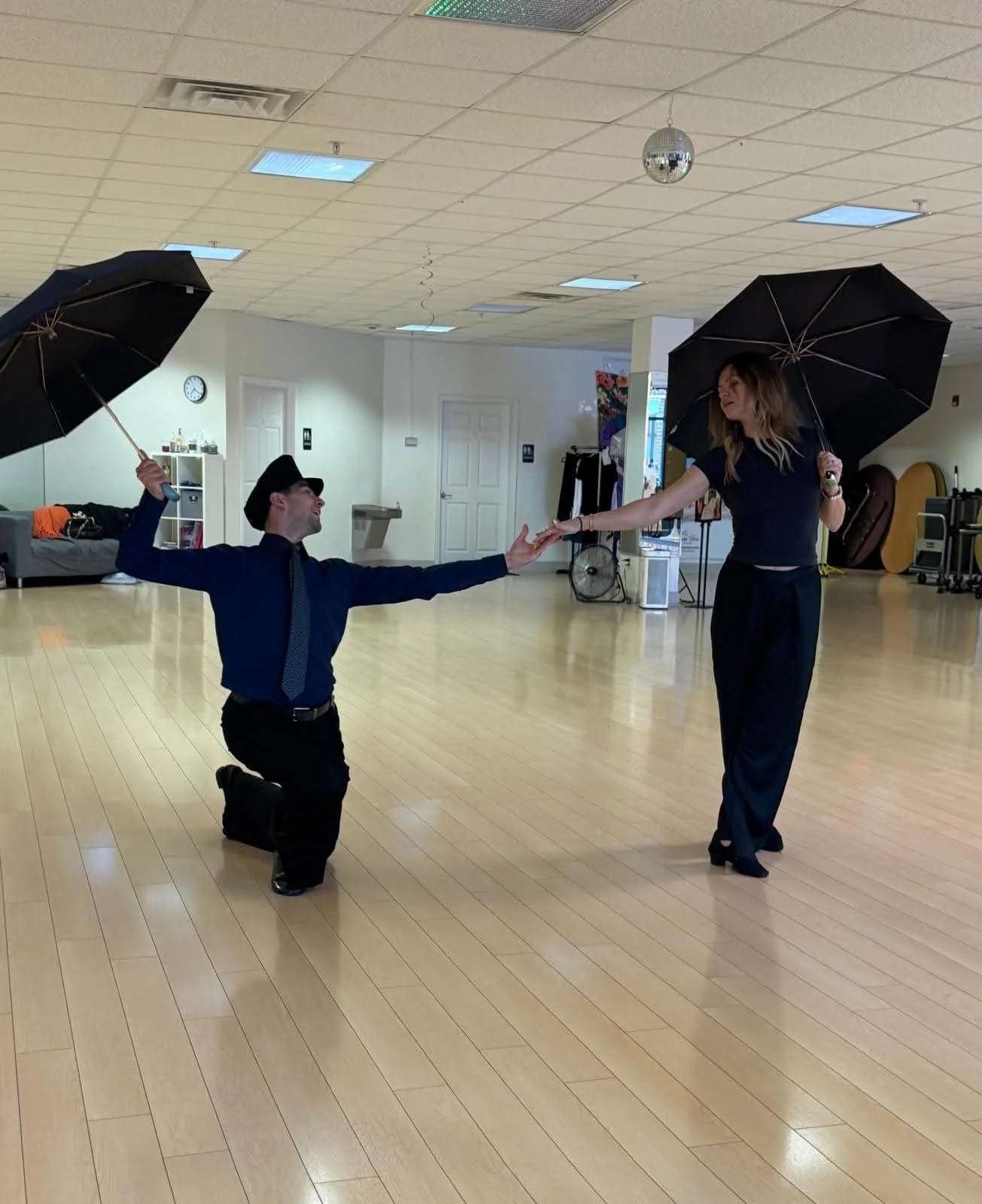 Studio participants extend their arms while holding umbrellas