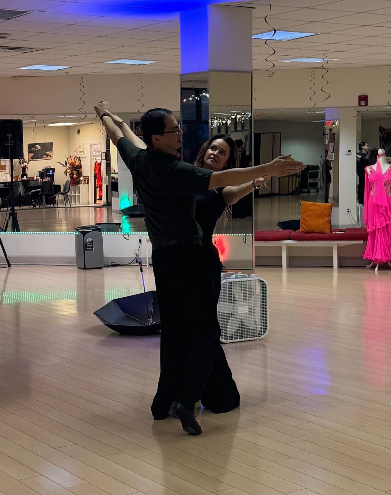 A dancer demonstrates an extended arm position on the studio floor