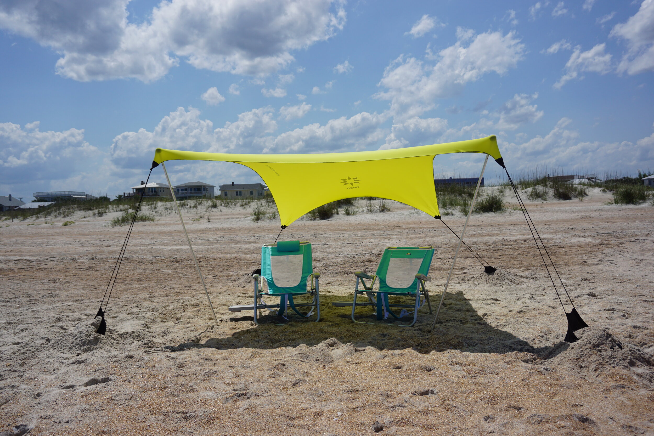 Neso shade tent with two chairs underneath on the beach