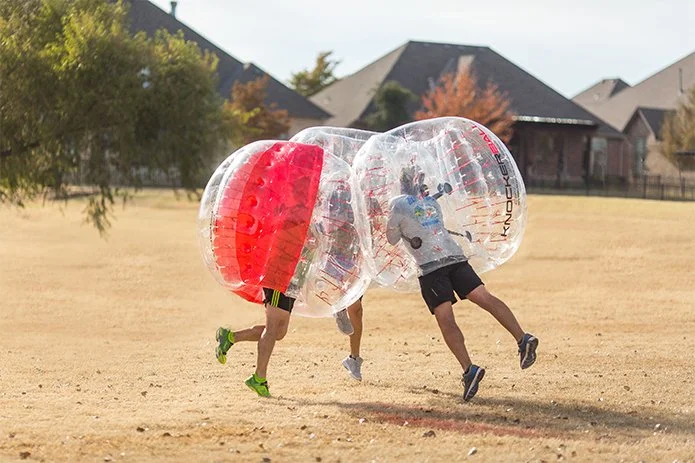 Players wearing knockerballs colliding during bubble soccer