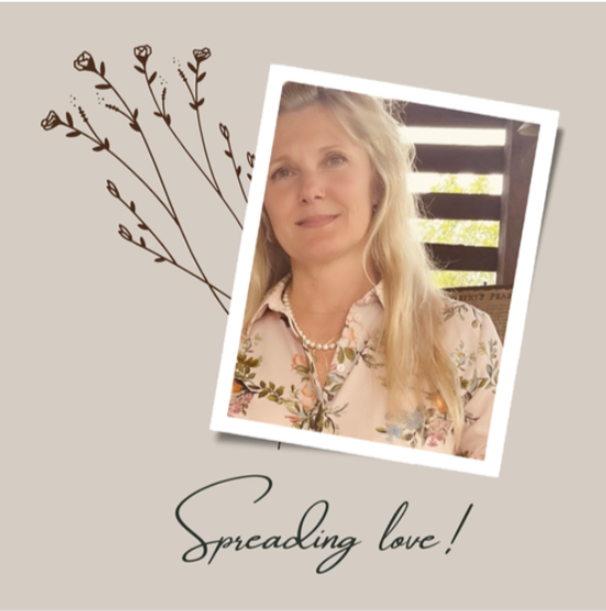 A woman with long blonde hair wearing a floral blouse and pearl necklace, smiling in front of a wooden fence with sunlight. Artistic illustration of sprigs of flowers to the left, with the text 'Spreading love!' below.