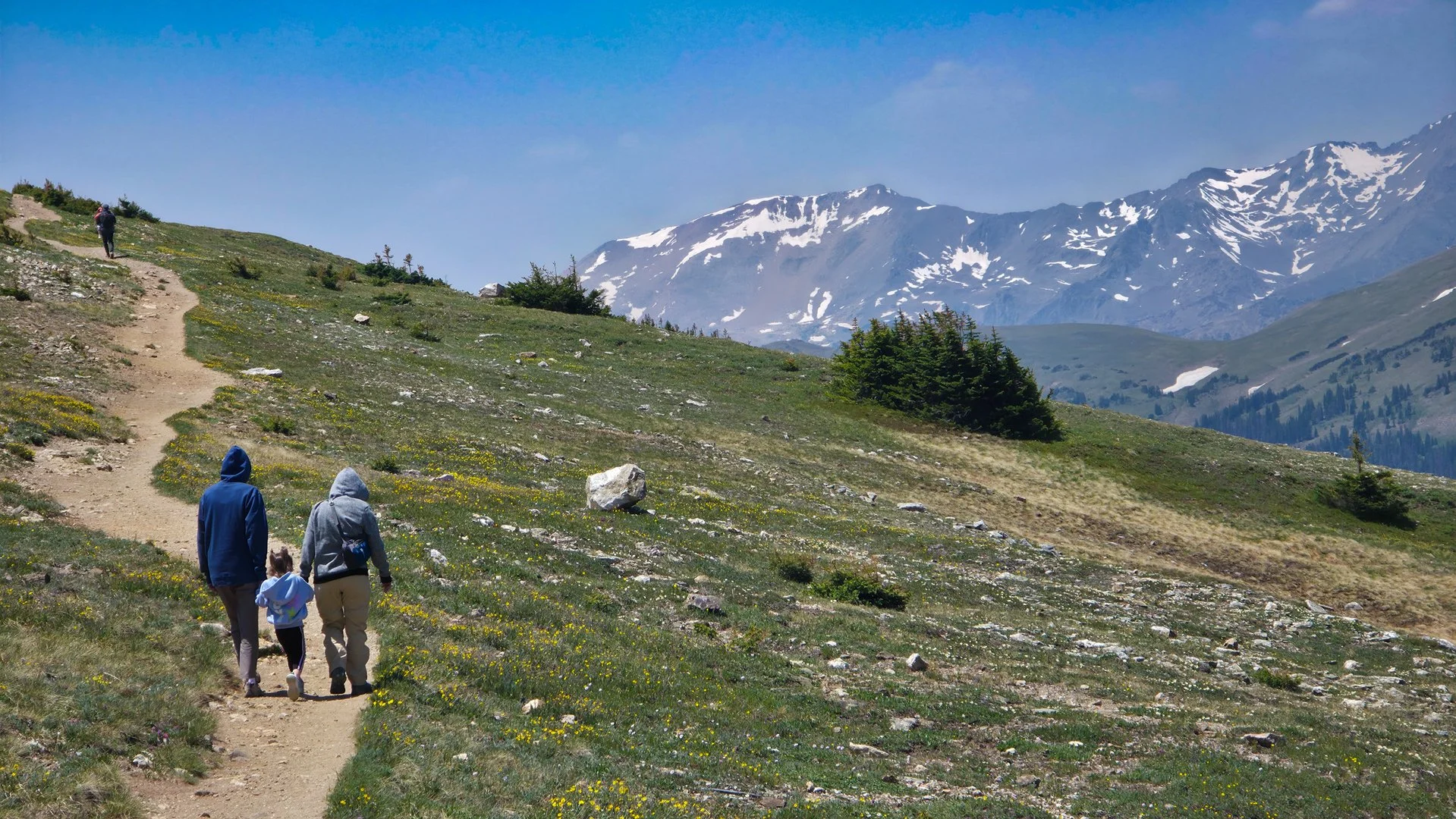 two adults holding hands with little girl hiking Ute trail in rocky mountains