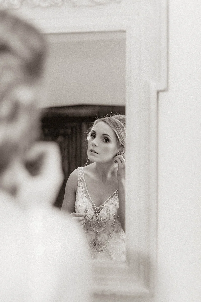 Bride checking her makeup in a gold mirror at Rockbeare Manor