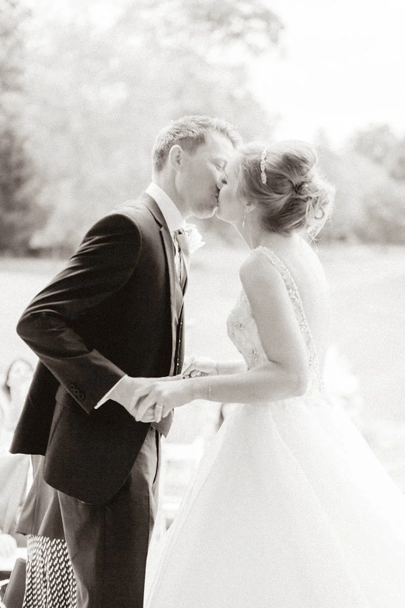 Bride and Groom first kiss in front of guests at outdoor wedding in Devon