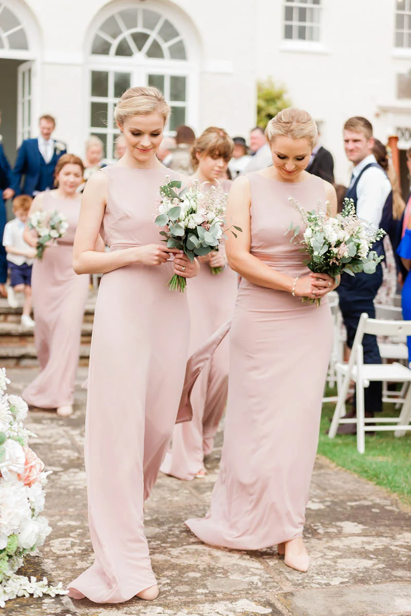 two blond bridesmaids wearing blush bridesmaids dresses at Rockbeare Manor wedding steps
