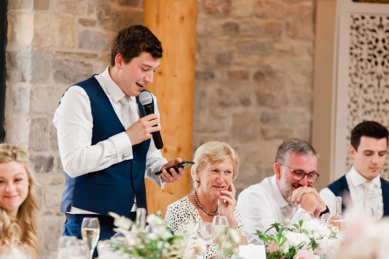 Groom stood in his navy suit reading his wedding day speech to guests at St Tewdrics House