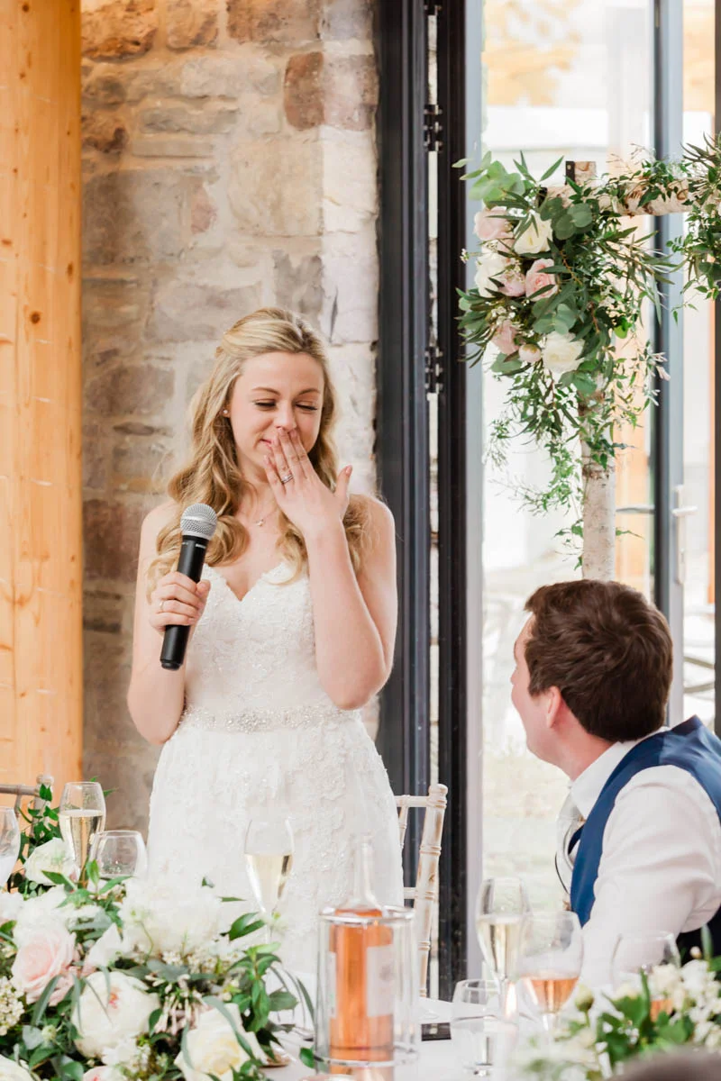 Bride stands to address her wedding guests at the table of the wedding breakfast