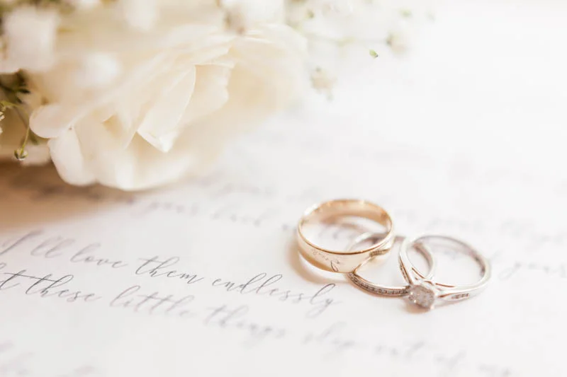 Wedding rings placed on lyrics to first dance song with a white rose