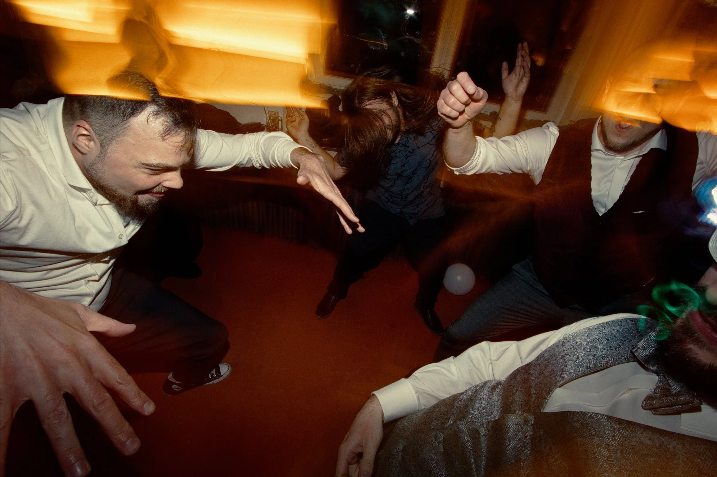 People dancing and having fun at a party, with motion blur and colorful lighting.