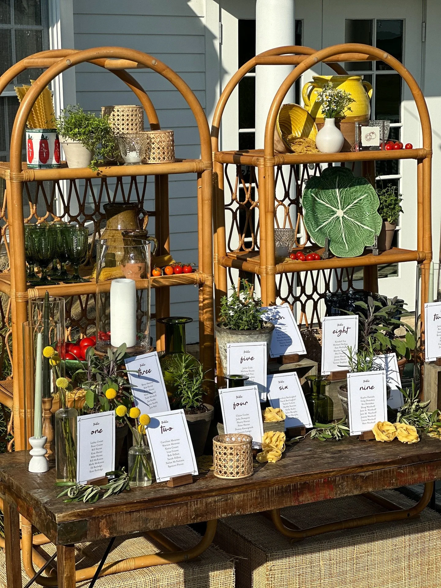 rehearsal dinner with an italian family dinner vibe. the seating chart was displayed on a vintage wood table with potted herbs, tomatoes and piles of pasta. rattan backbar shelves accessorized with authentic jugs, cane candles, green glassware and ce