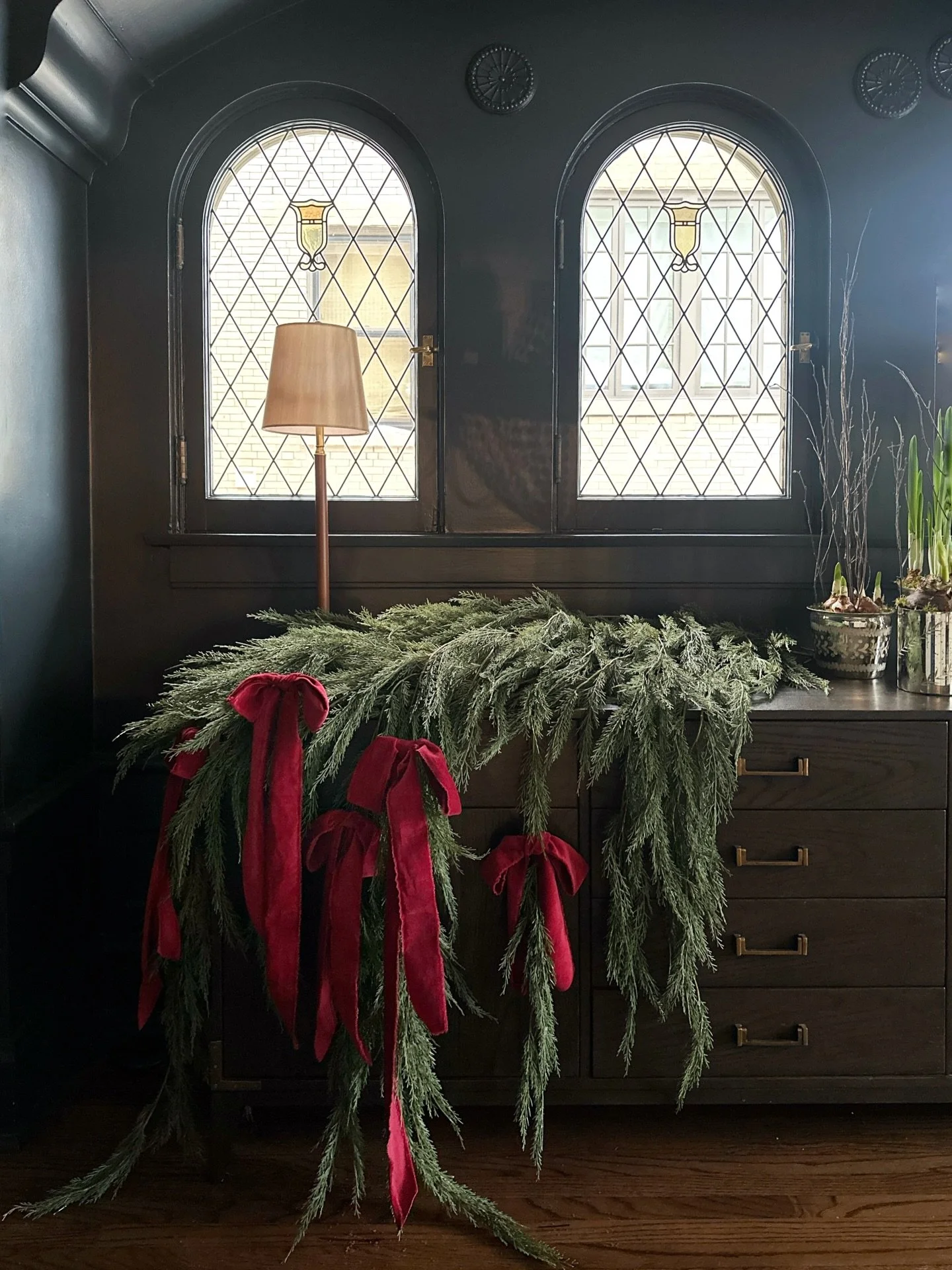 we wanted this dining room decor to be sophisticated, chic and simple. we used full and layered cedar garlands to create the textured base and juxtaposed the greens with several velvety red ribbons. she&rsquo;s striking and different and definitely a
