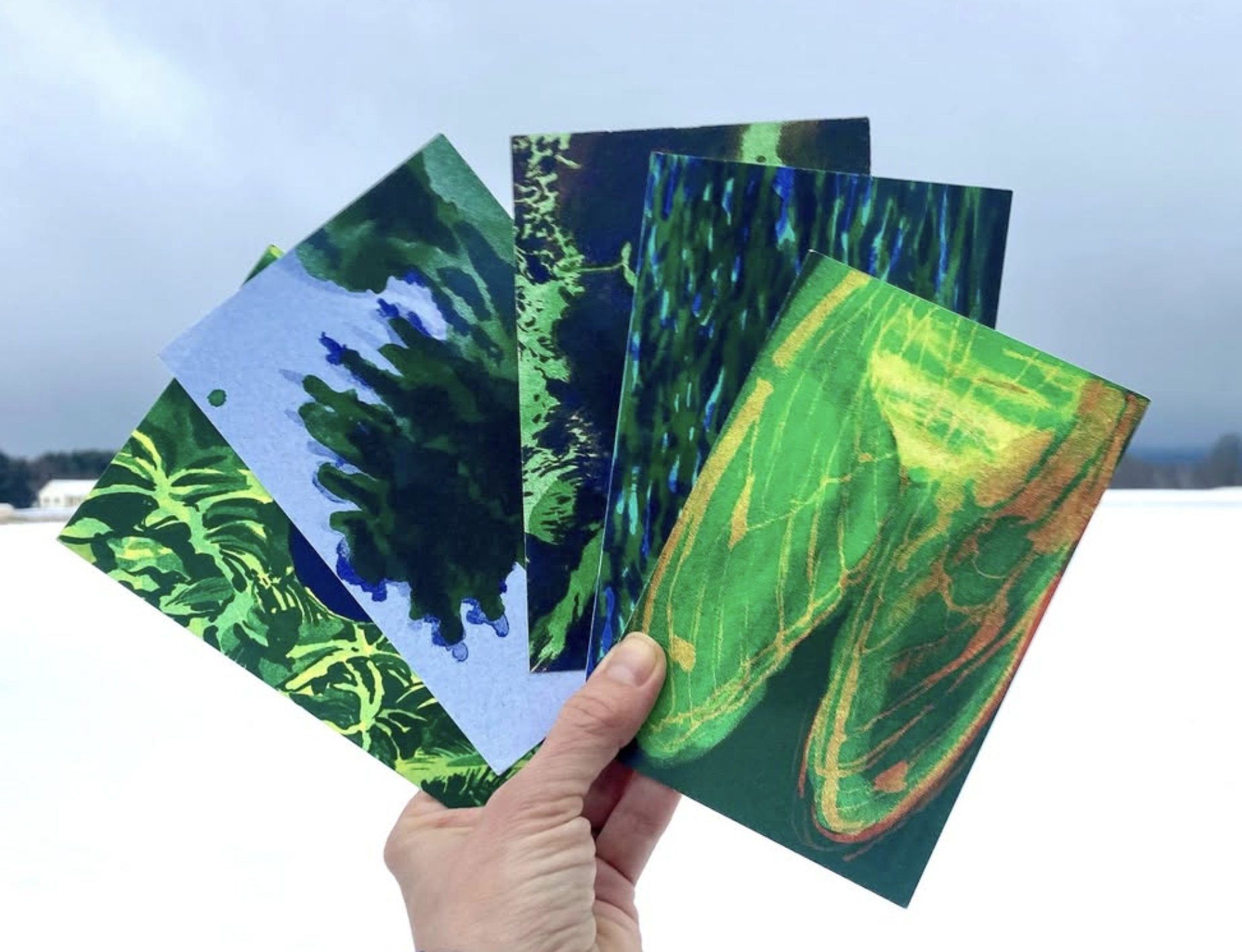 photo of a hand holding several colorful postcards