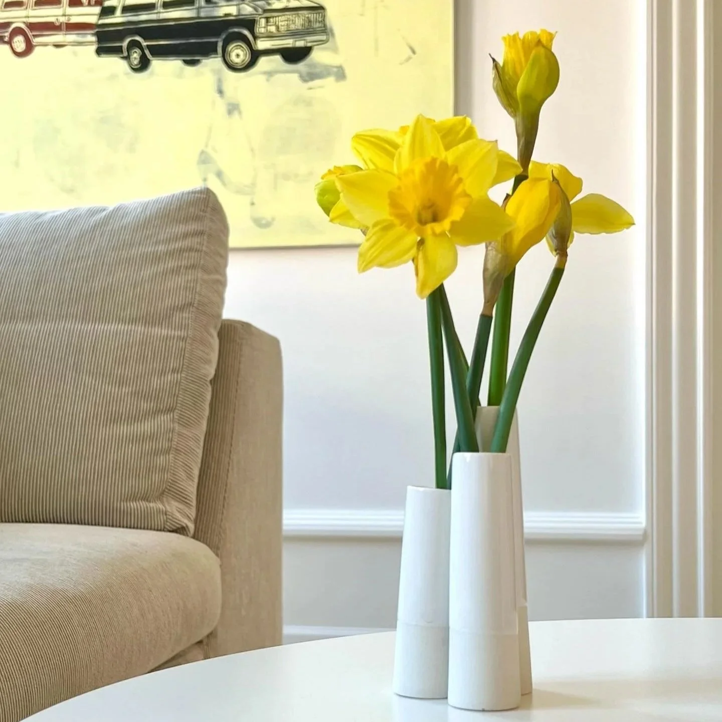 Handmade white Danish tube vase with daffodils on white minimalist table