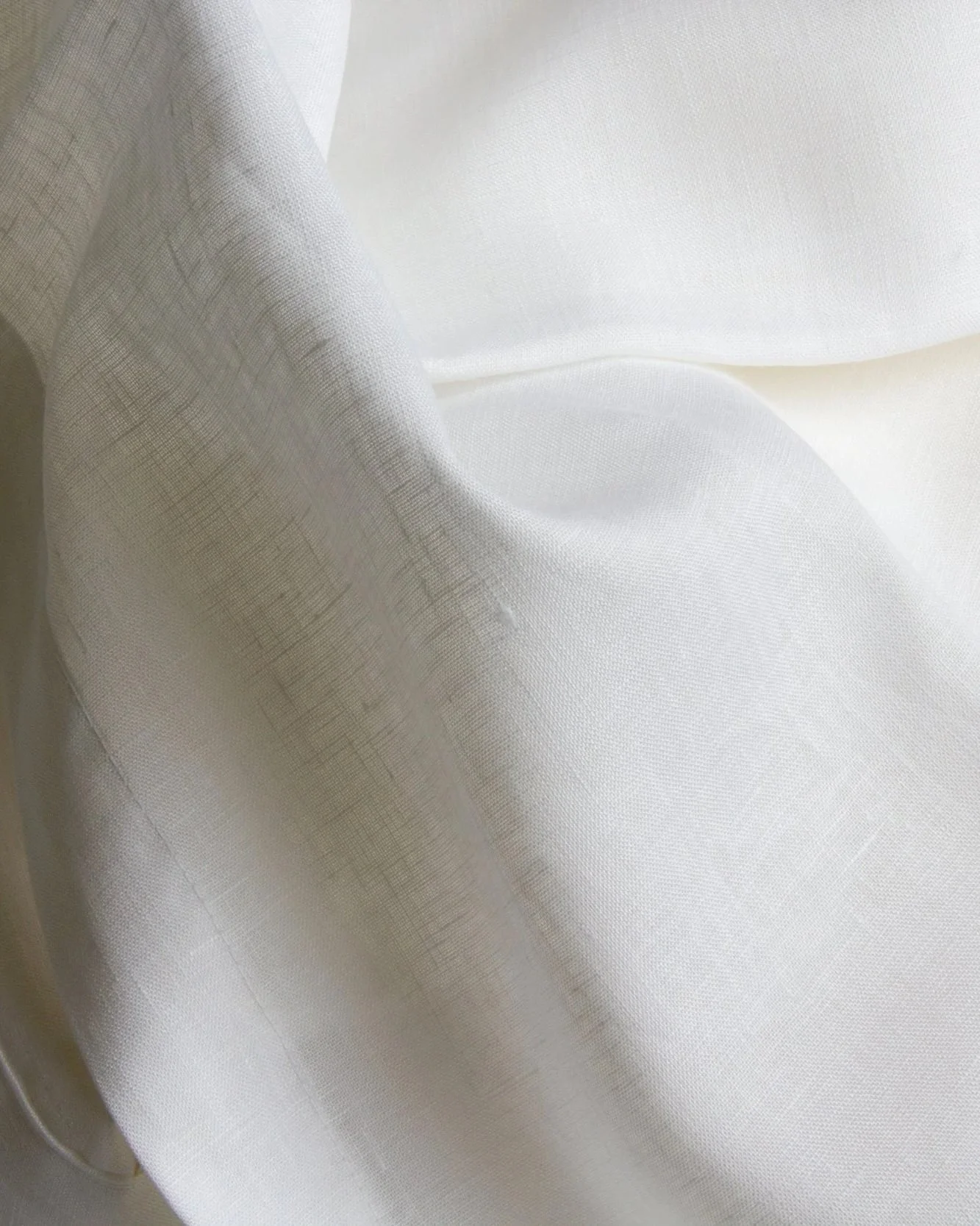 Soft white linen tablecloth draped over a dining table, showcasing the natural texture of handcrafted linen.